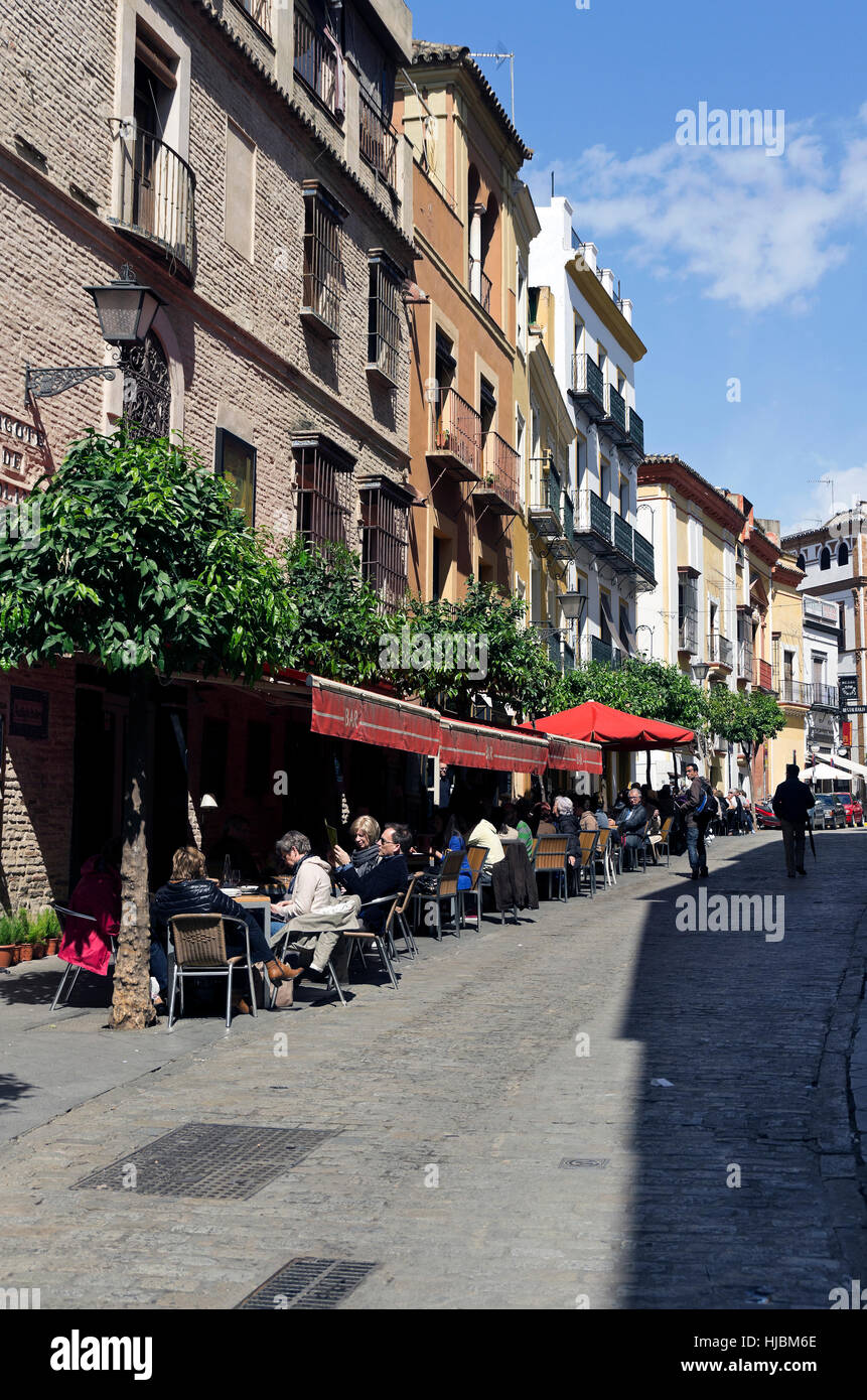 People eating at sidewalk cafes in front of picturesque buildings, on cobble stone streets. Stock Photo