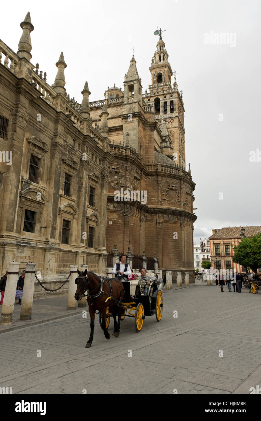 Horse-drawn carriage makes its way down the street past the cathedral with father, mother and little girl riding in back. Stock Photo