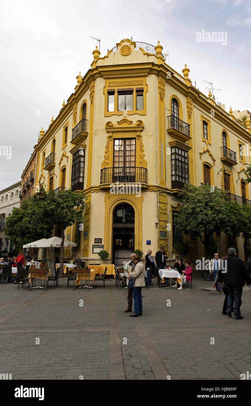 Tourist standing and eating in front of El Giraldillo restaurant on chilly day. Stock Photo