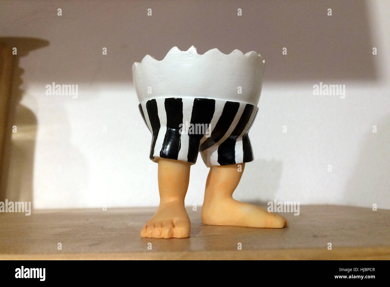 Egg cup in shape of broken egg shell with two human legs. Kitsch example. Stock Photo