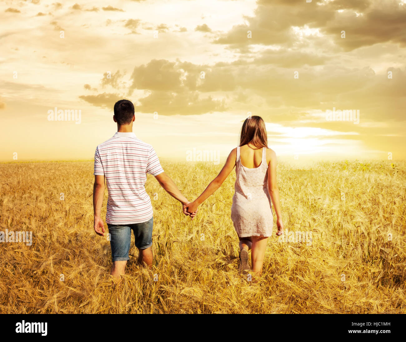 Young Couple In Love Walking In The Field Holding Hands