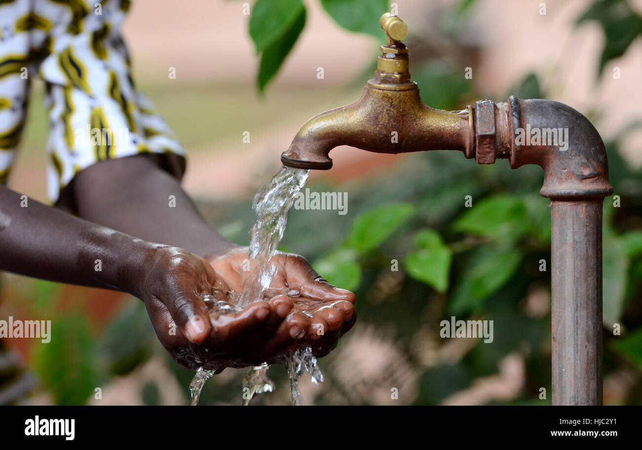Climate Change Symbol: Handful Of Water Scarsity for Africa Symbol. Hand of an African black boy with water pouring from a tap. Stock Photo