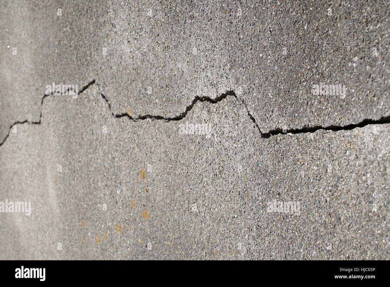Crack in the structure of a grey concrete wall Stock Photo