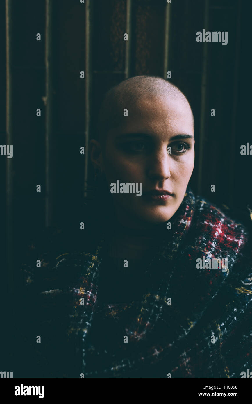 Low key portrait of young woman with shaved head Stock Photo