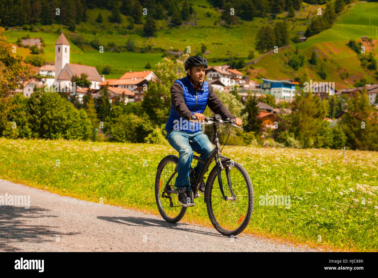 Mid adult man cycling on village path in Vinschgau Valley, South Tyrol, Italy Stock Photo