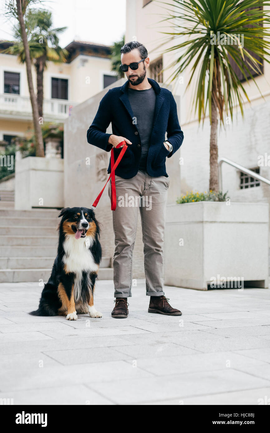 Mid adult man standing with pet dog in city square Stock Photo Alamy