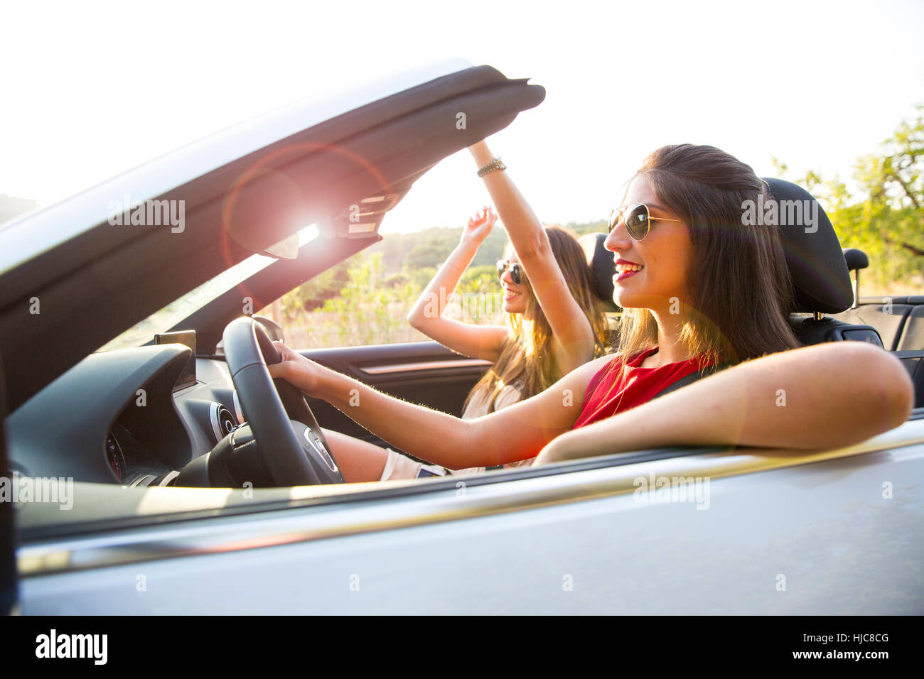Two young women driving on rural road in convertible, Majorca, Spain Stock Photo