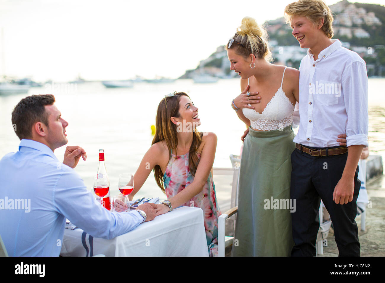 Two couples greeting at waterfront restaurant, Majorca, Spain Stock Photo