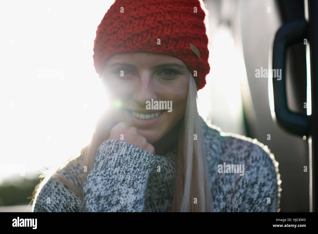 Sunlit portrait of young woman in red knit hat Stock Photo