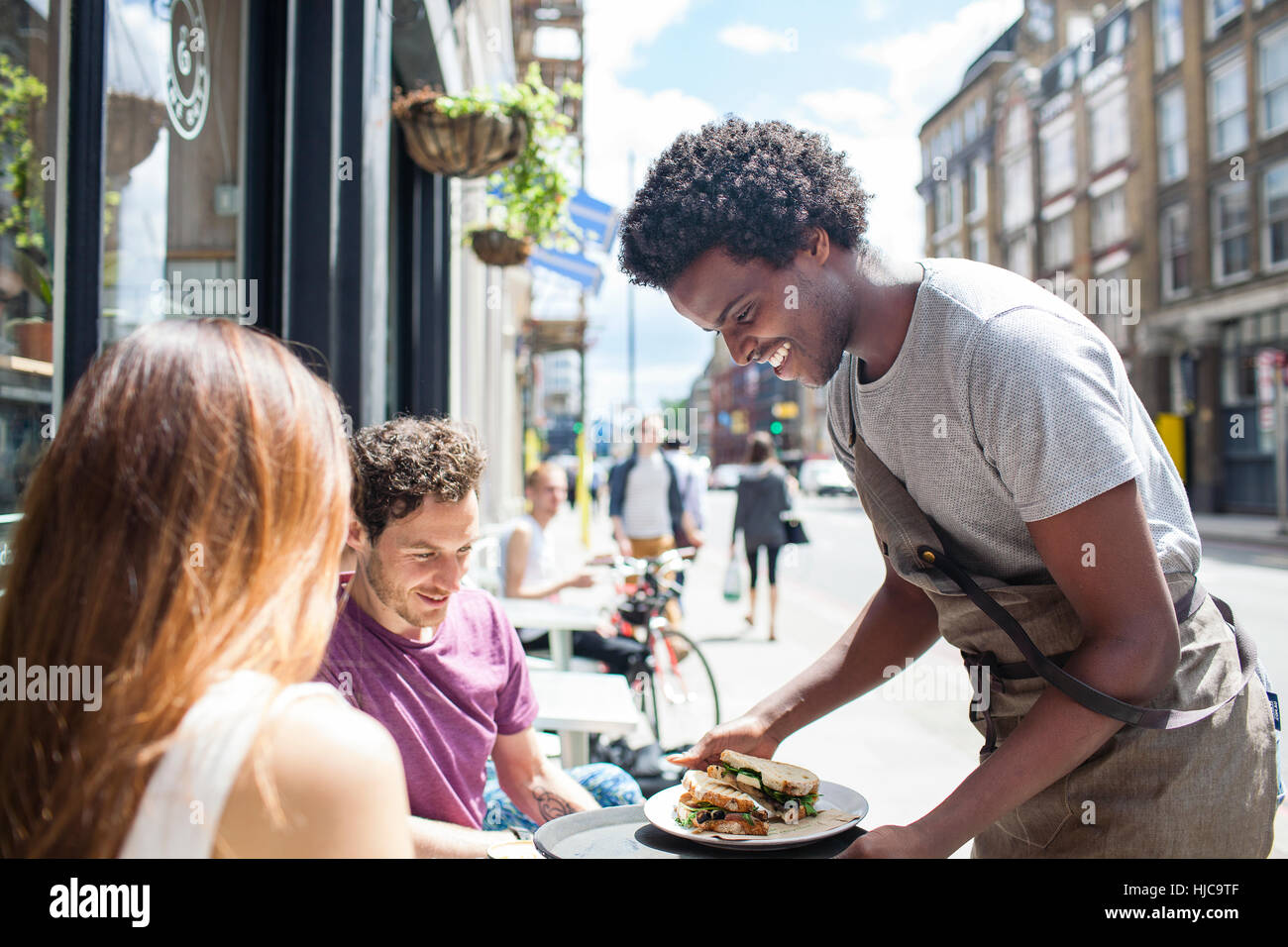 Waiter serving lunch to couple at city sidewalk cafe Stock Photo