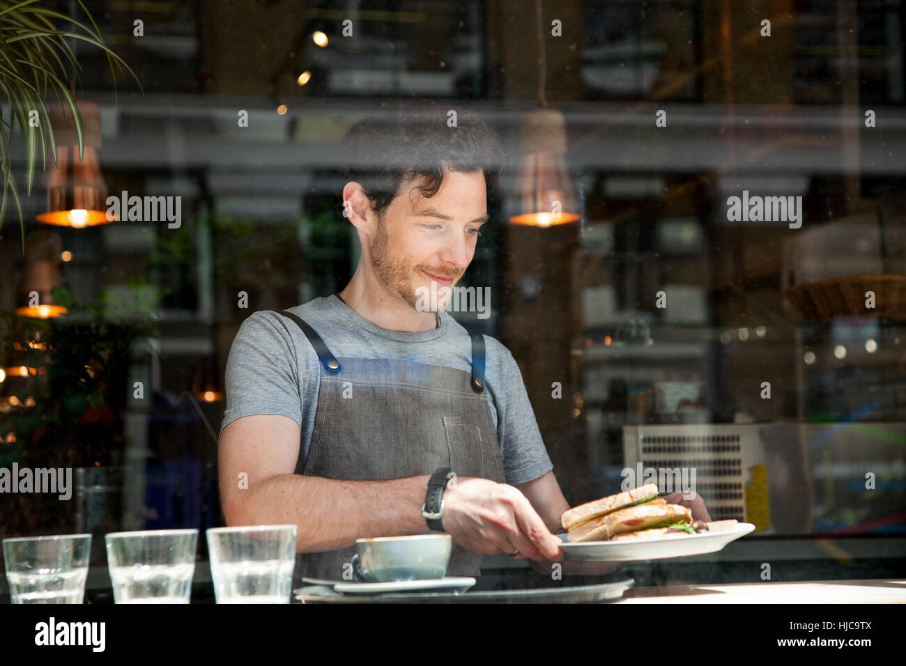 Waiter preparing order at cafe window Stock Photo