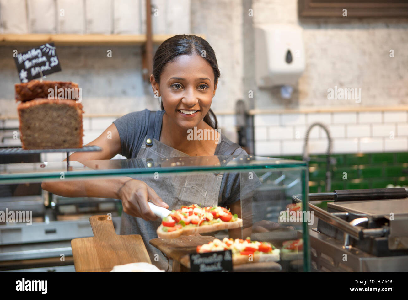Waitress serving open sandwich from cafe display cabinet Stock Photo
