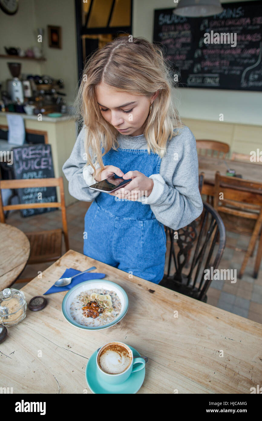 Young woman in cafe, using smartphone Stock Photo