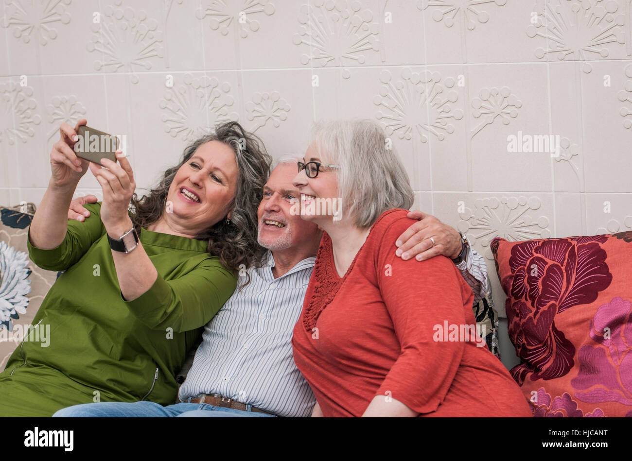 Happy seniors taking selfie on couch Stock Photo