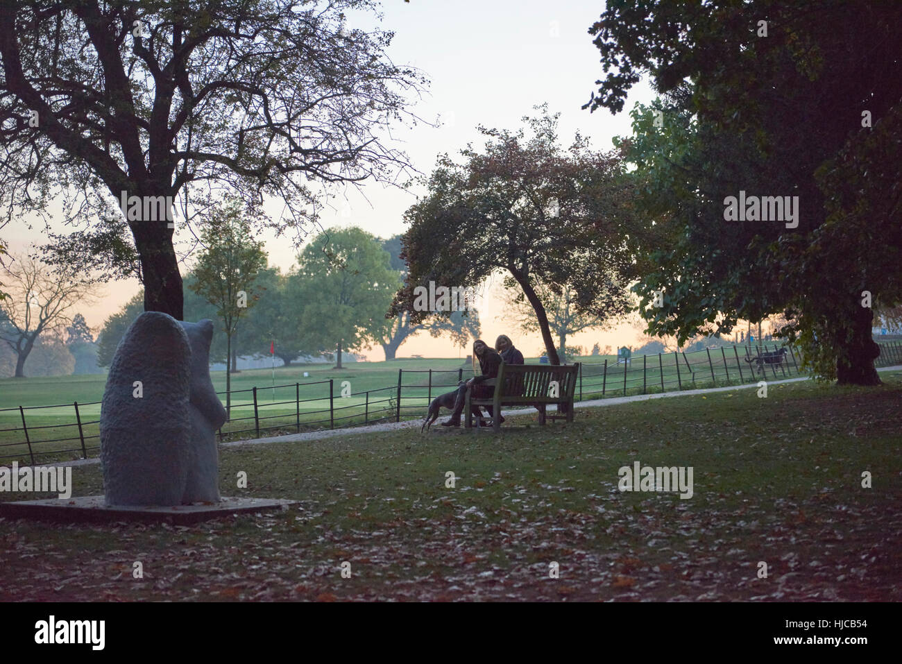 Silhouetted view of senior woman and daughter sitting on park bench in ...
