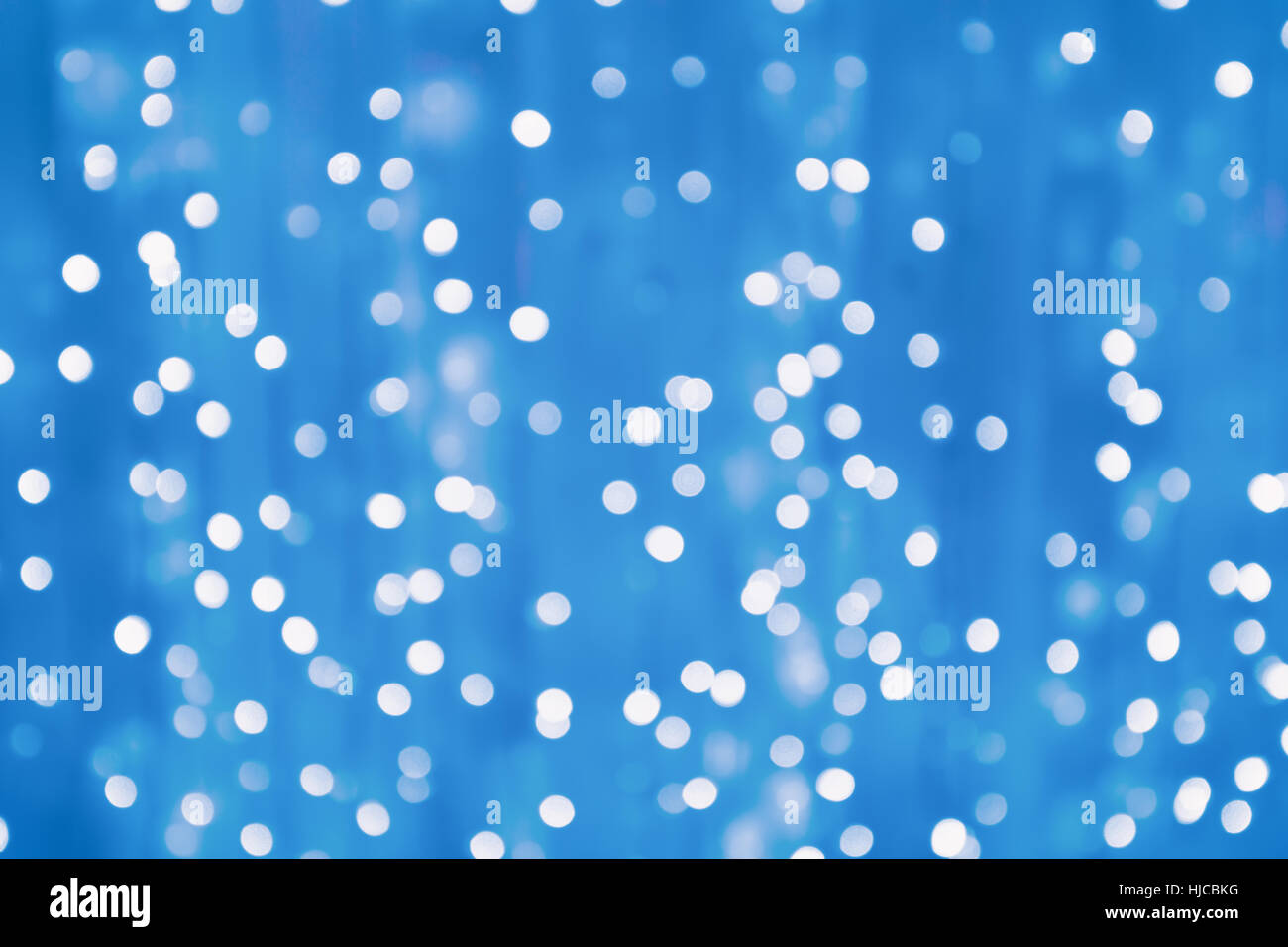Blurry bokeh bright light from tiny lamps on blue screen background at night Stock Photo
