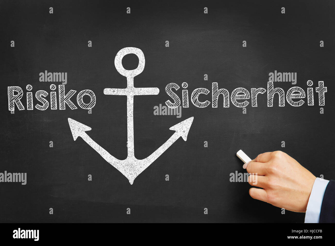 Hand writing German words 'Risiko' (risk) and 'Sicherheit' (safety) on blackboard Stock Photo