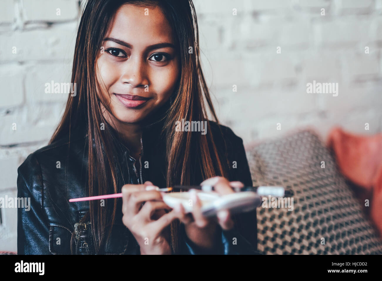 Beautiful girl in leather jacket doing makeup Stock Photo