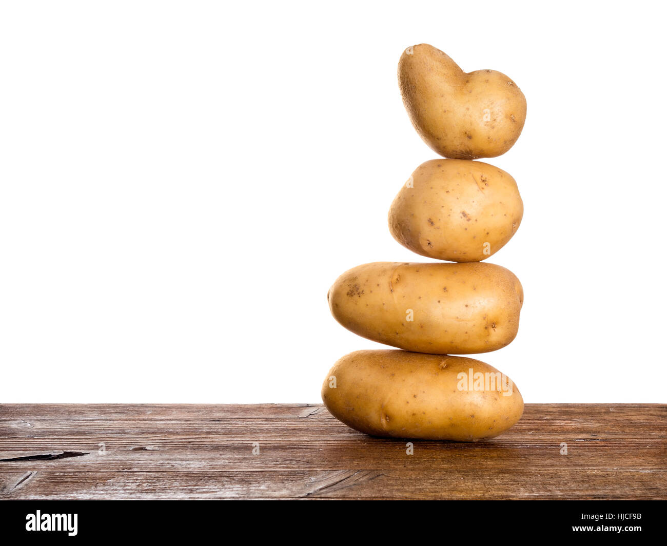 Zen style potato tower. Balanced diet! Baking, cooking etc. On rustic work surface.Isolated against white behind. Stock Photo