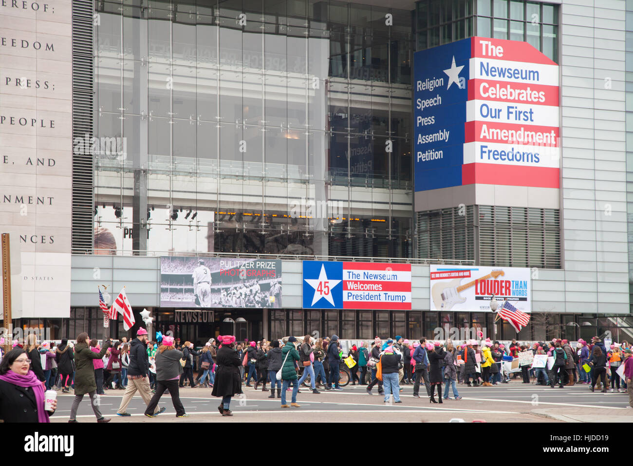 Washington, DC, USA. January 21st, 2017. Women's March on Washington, DC: The Newseum with the 1st Amendment to the Constitution edged on its facade along with inaugural sign welcoming President Trump contrasts with crowds gathering to protest President Trump's positions on women's and other human rights on women's and other human rights. Credit: Dasha Rosato/Alamy Live News Stock Photo