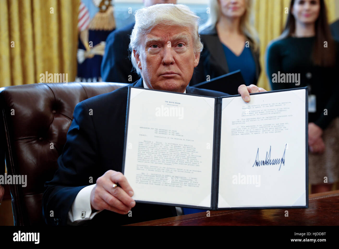 Washington, DC, USA. 24th Jan, 2017. US President Donald Trump displays one of five executive orders he signed related to the oil pipeline industry in the oval office of the White House in Washington, DC, USA, 24 January 2017. President Trump has a full day of meetings including one with Senate Majority Leader Mitch McConnell and another with the full Senate leadership. Credit: Shawn Thew/Pool via CNP/dpa/Alamy Live News Stock Photo