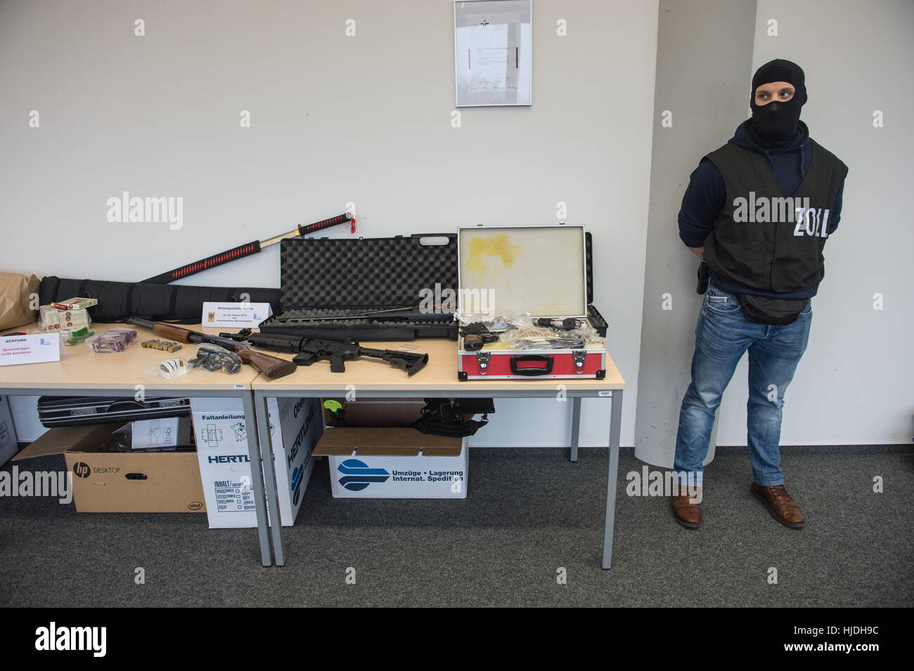 An officer of the customs investigation protects illegal confiscated weapons in Frankfurt/Main, Germany, 25 January 2017. Looking for weapons that were illegaly bought on the internet, customs investigators searched apartments and offices in eleven states and confiscated numerous weapons. Photo: Andreas Arnold/dpa Stock Photo