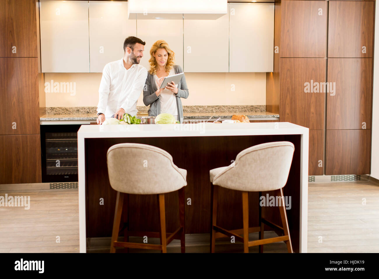 Couple in home kitchen using electronic tablet and preparing food Stock Photo