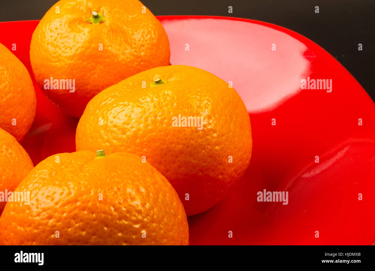tangerines in a red plate on black background Stock Photo Alamy