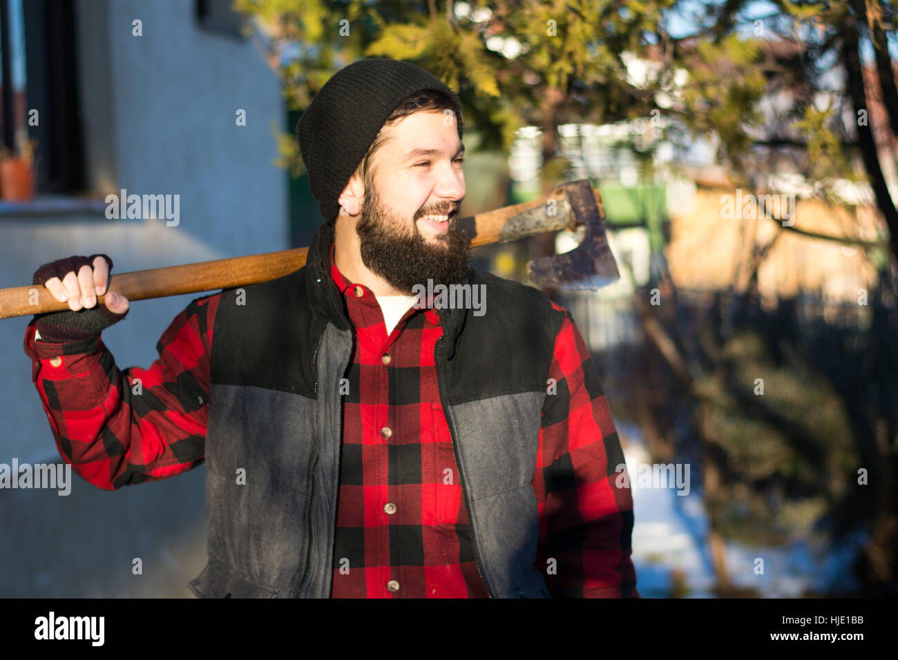 bearded lumberjack with an axe in snow outside Stock Photo