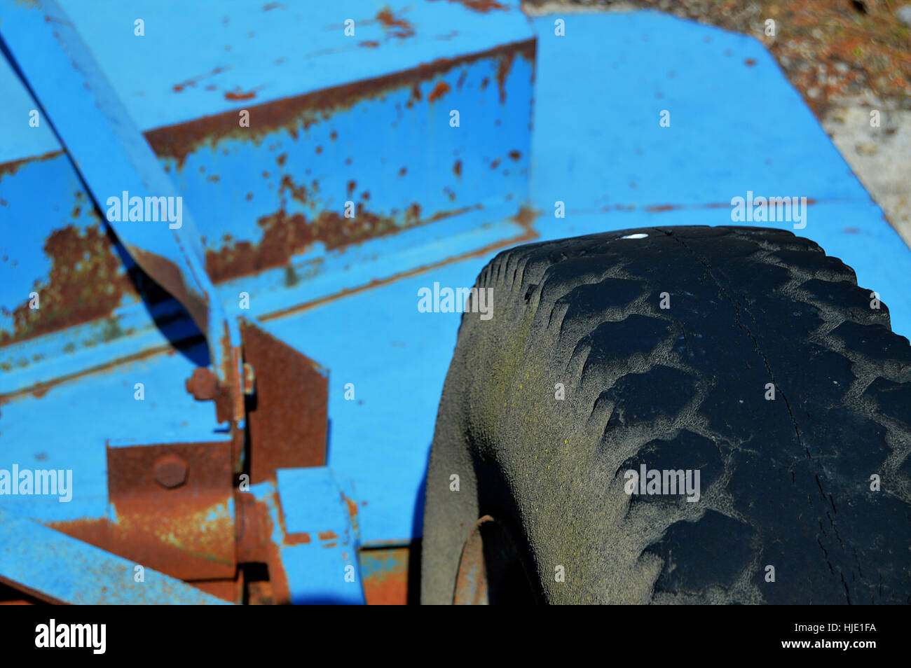 A blue industrial lawn mower sitting deserted on  broken concrete and weeds. Stock Photo