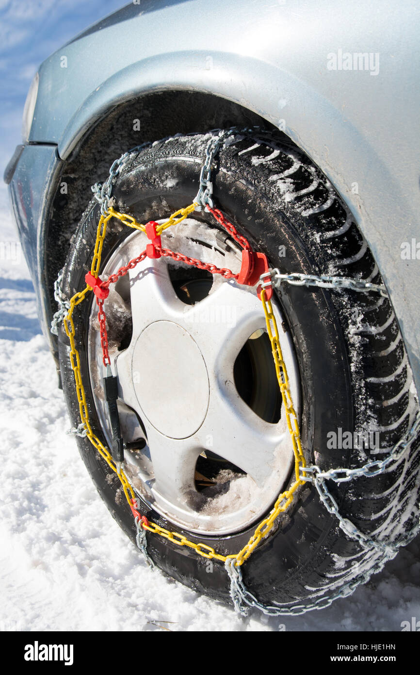 Snow chains mounted on car wheels on winter day Stock Photo