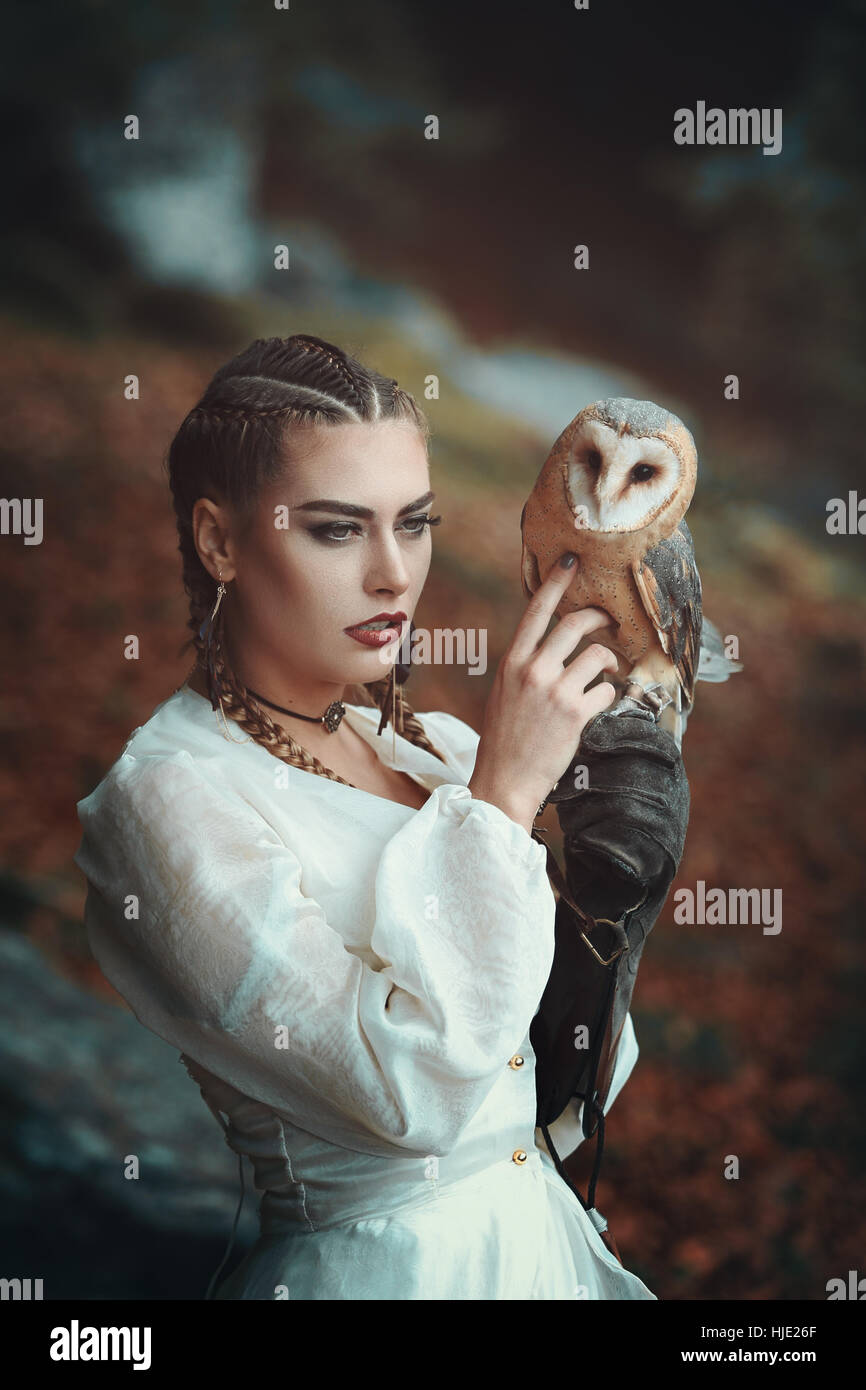 Beautiful woman with elegant barn owl . Fantasy and falconry Stock Photo