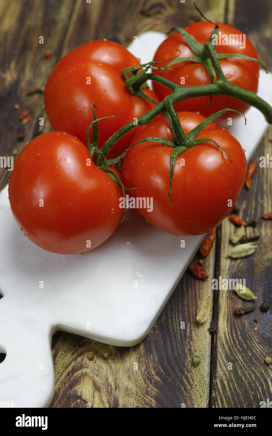 Raw Organic Red Tomatoes on the Vine on white marble plank Stock Photo ...