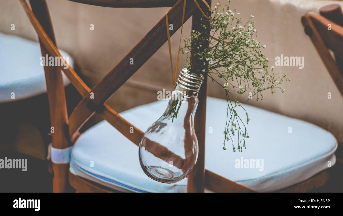 Original wedding floral decoration, minivases and bouquets of flowers hanging from the chair