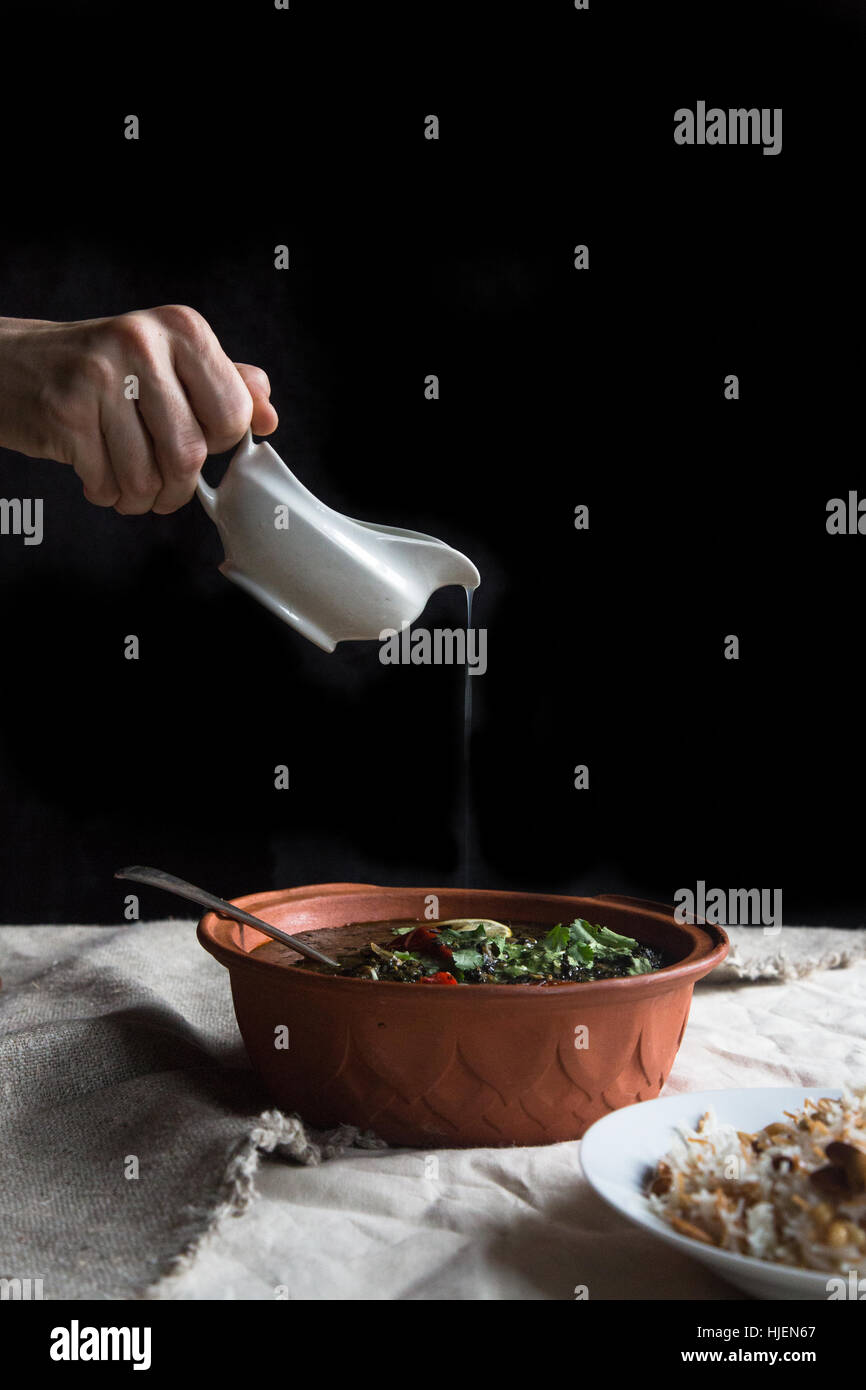 hand with sauce boat over stew Stock Photo