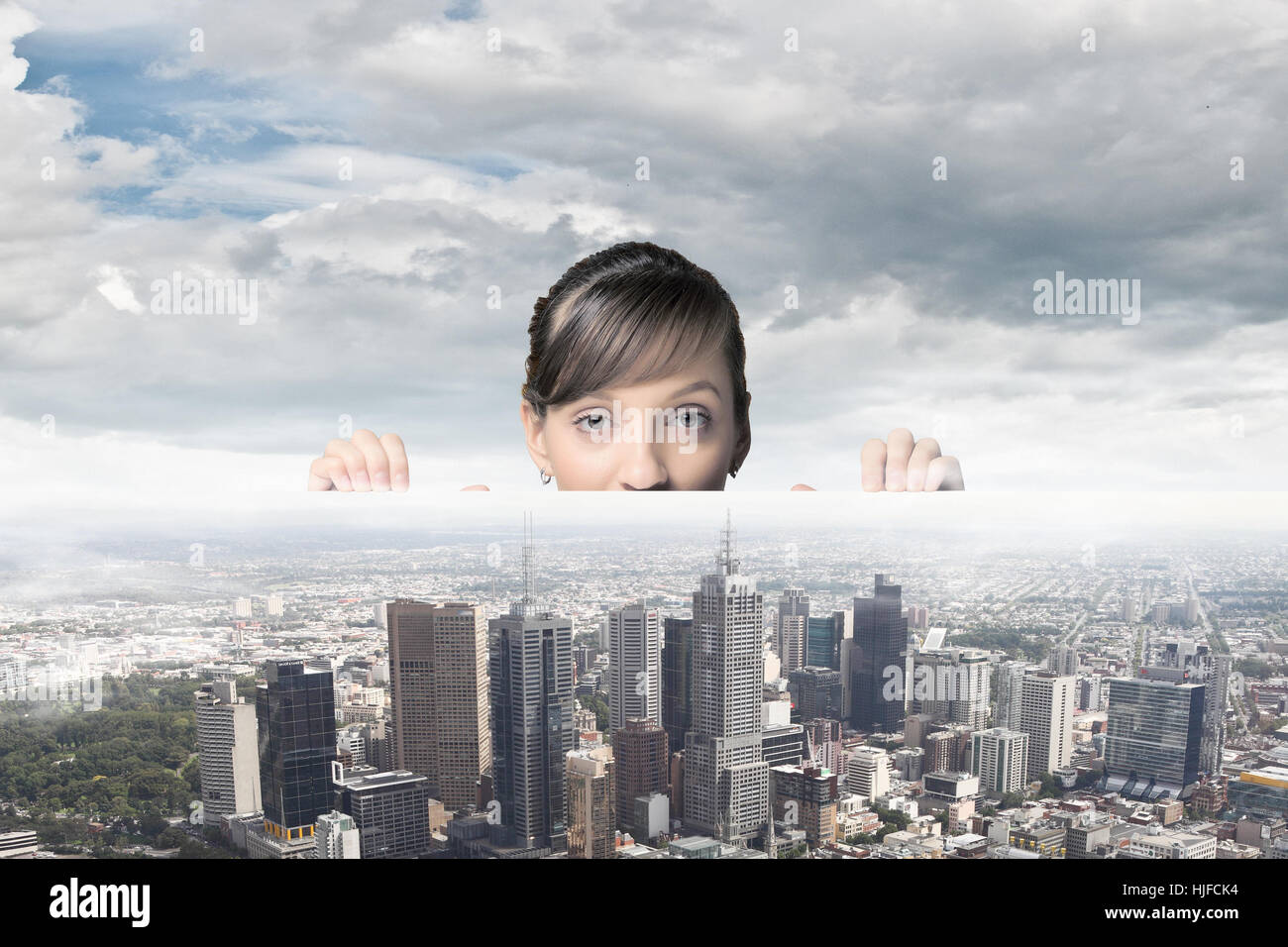 Half of face of businesswoman looking from under table at city model ...