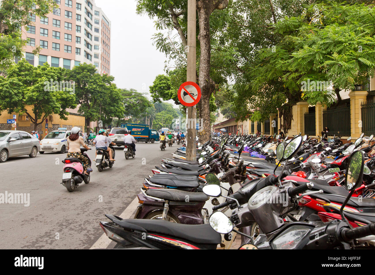 City street, row of motorcycles & scooters parked on sidewalk Stock