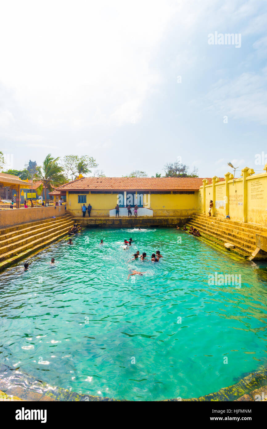 Sri Lankan people swimming in the Keerimalai Hot Springs, a tourist attraction on the northern coast of Jaffna. Vertical Stock Photo