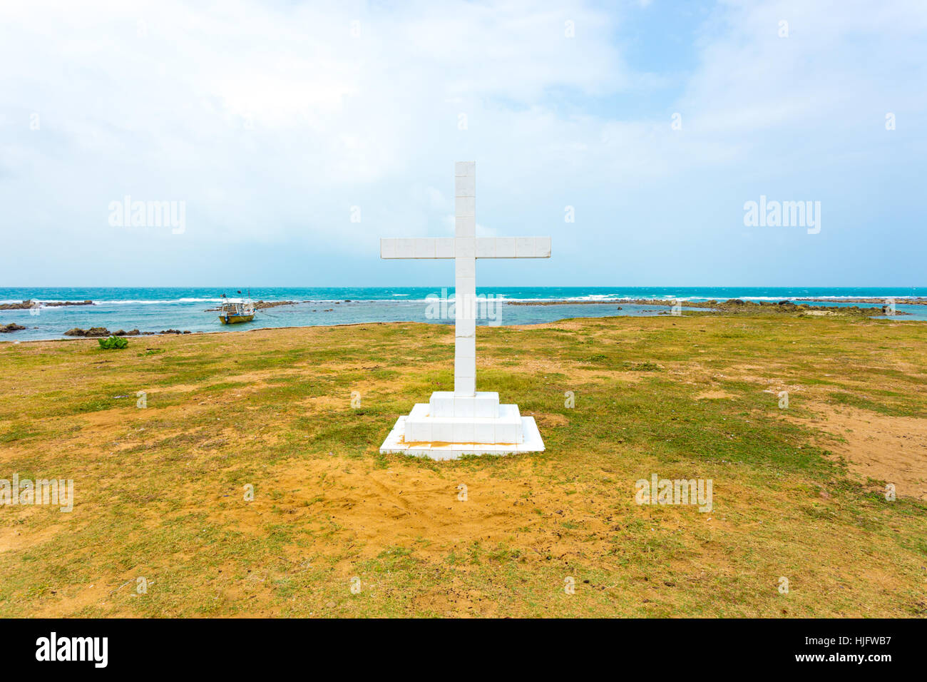White cross is planted outside of Saint Thomas Church along the ocean in Point Pedro, Jaffna, Sri Lanka. Horizontal Stock Photo