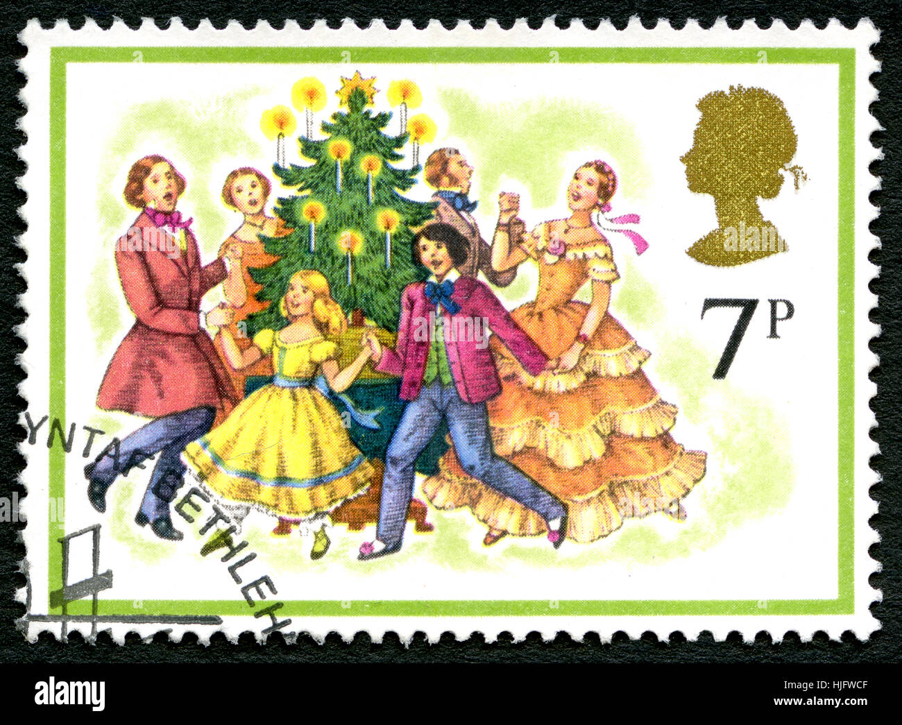 UK - CIRCA 1980s: A postage stamp from the UK - a festive and happy Christmas scene of a family dancing around the Xmas tree. Stock Photo