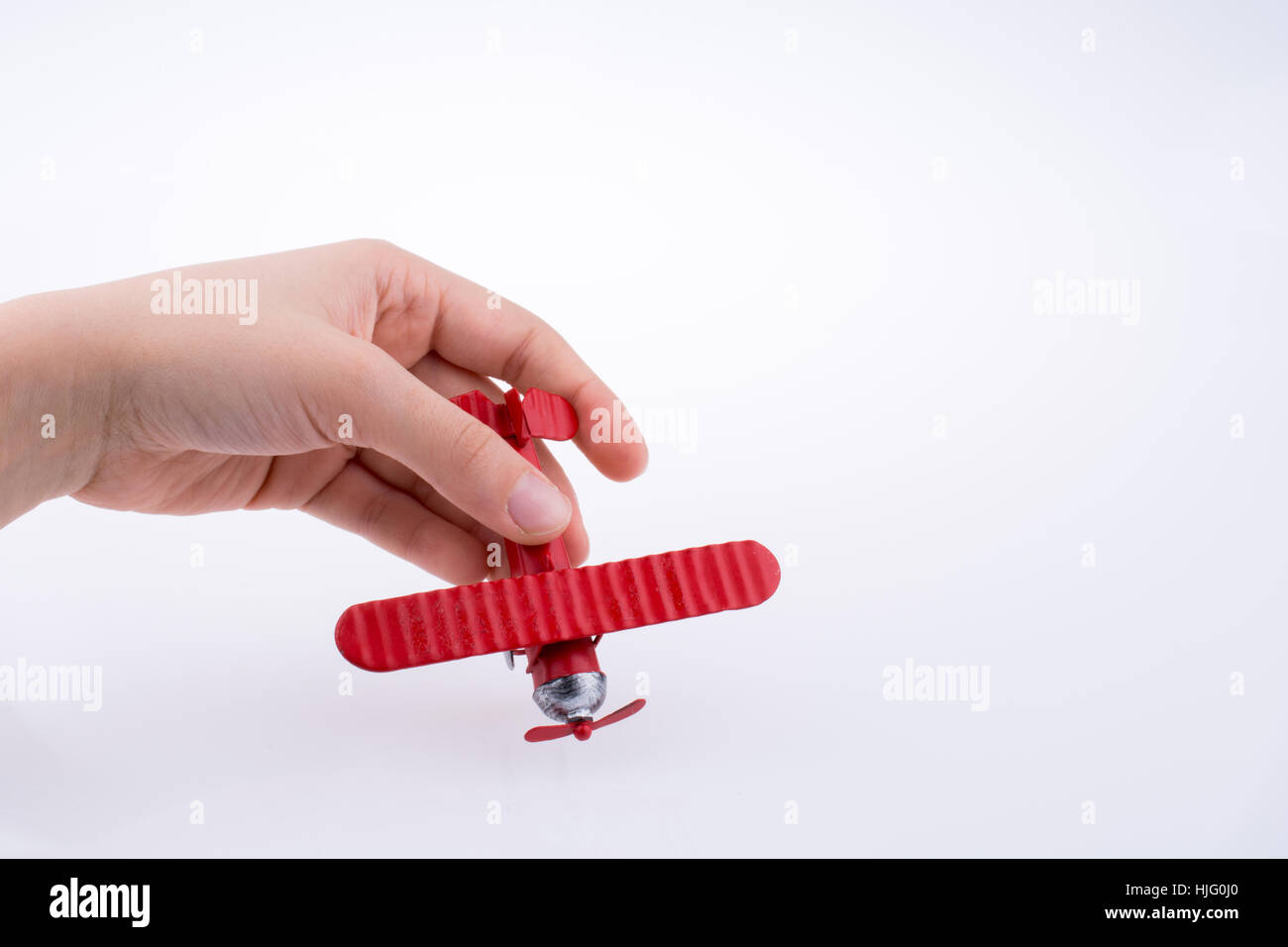 Hand holding a red toy plane on a white background Stock Photo - Alamy