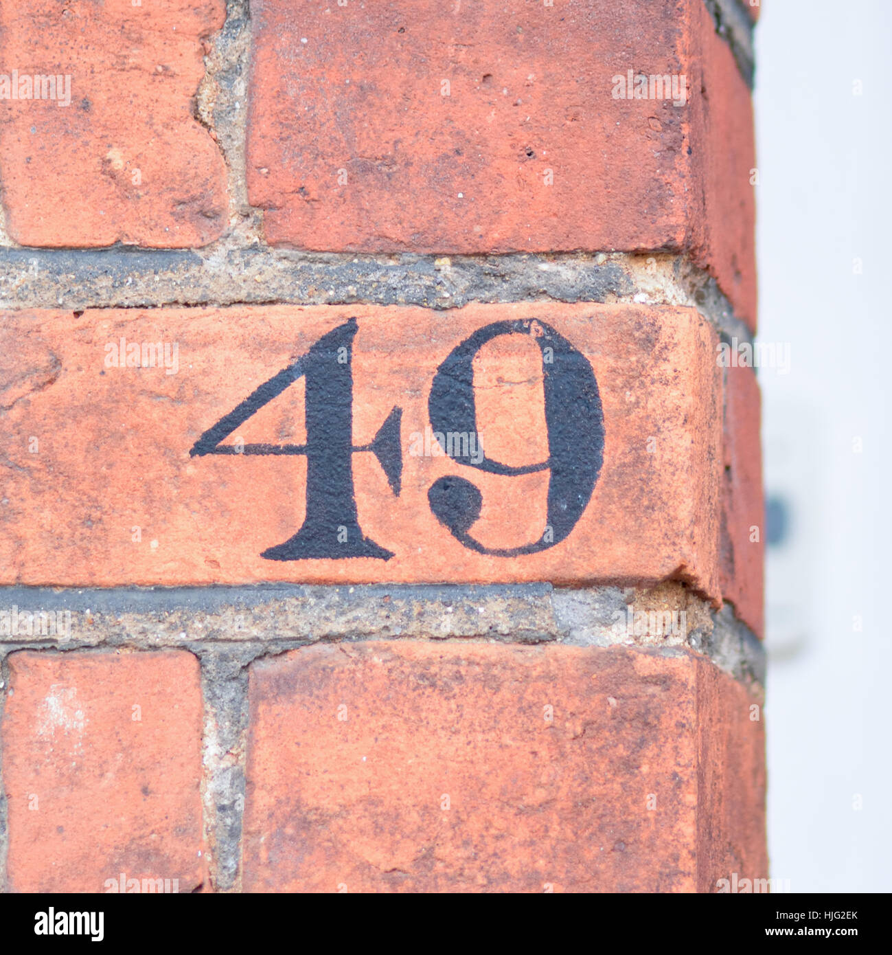 House number 49 sign painted black on red brick wall Stock Photo