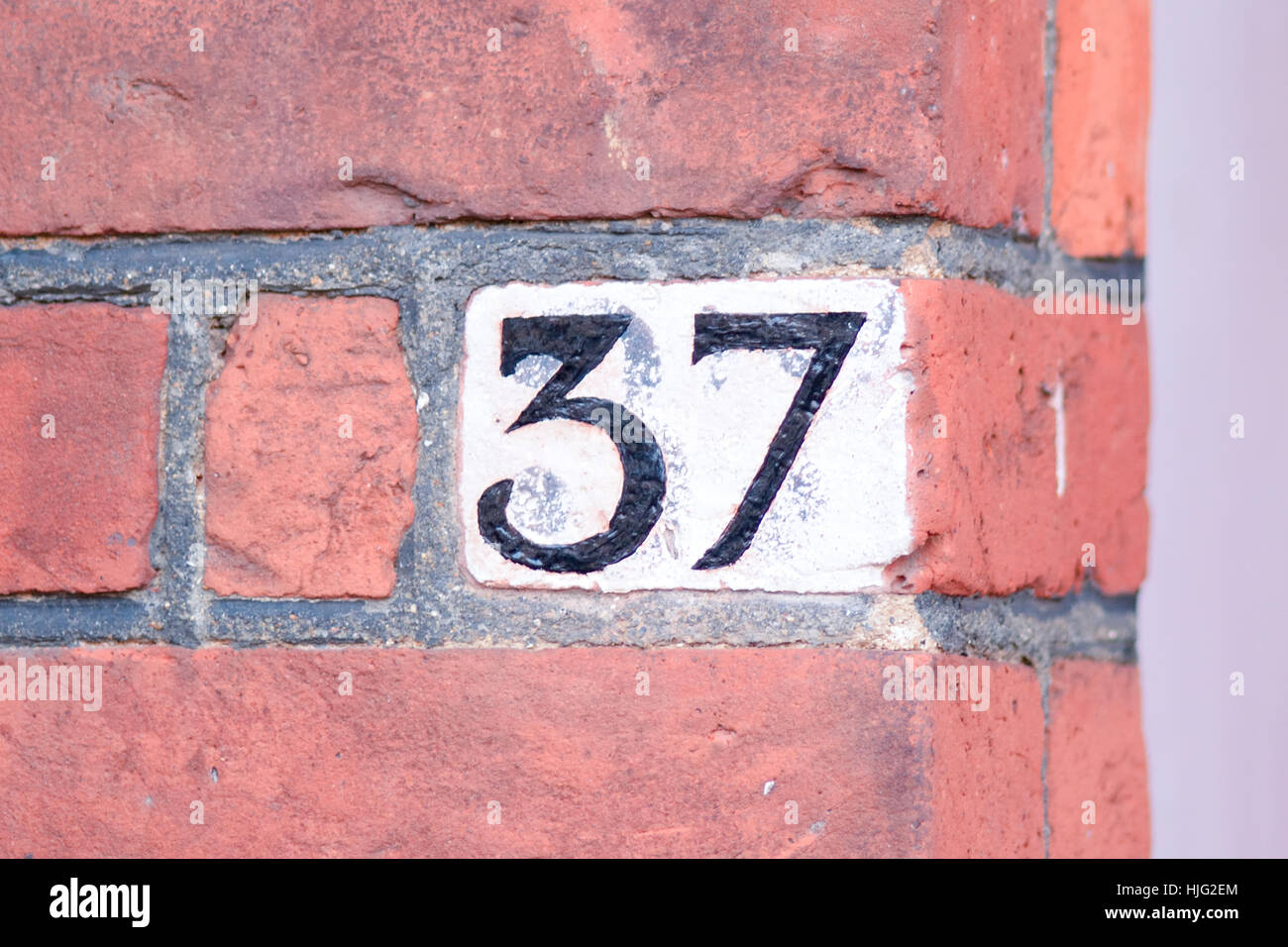 house-number-37-sign-painted-black-on-white-background-on-wall-stock