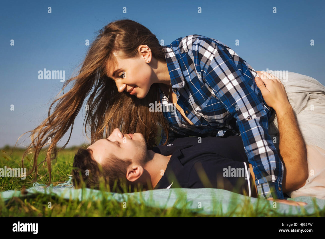teenagers lie on the green summer grass. girl on top of the guy Stock Photo