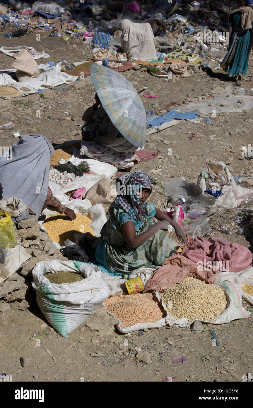 Market in Mekelle, Ethiopia, littered with rubbish, an older woman selling spices and one under an umbrella as sun protection Stock Photo