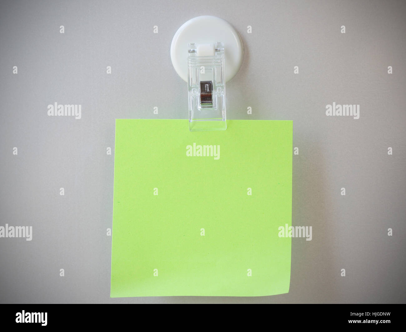 Light green post it clip by clip magnet on gray refrigerator background. Stock Photo
