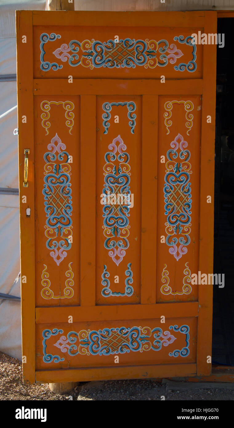 Orange Mongolian ger or yurt paneled wooden door hand painted with elaborate scroll pattern. Interior side of door shown. Stock Photo