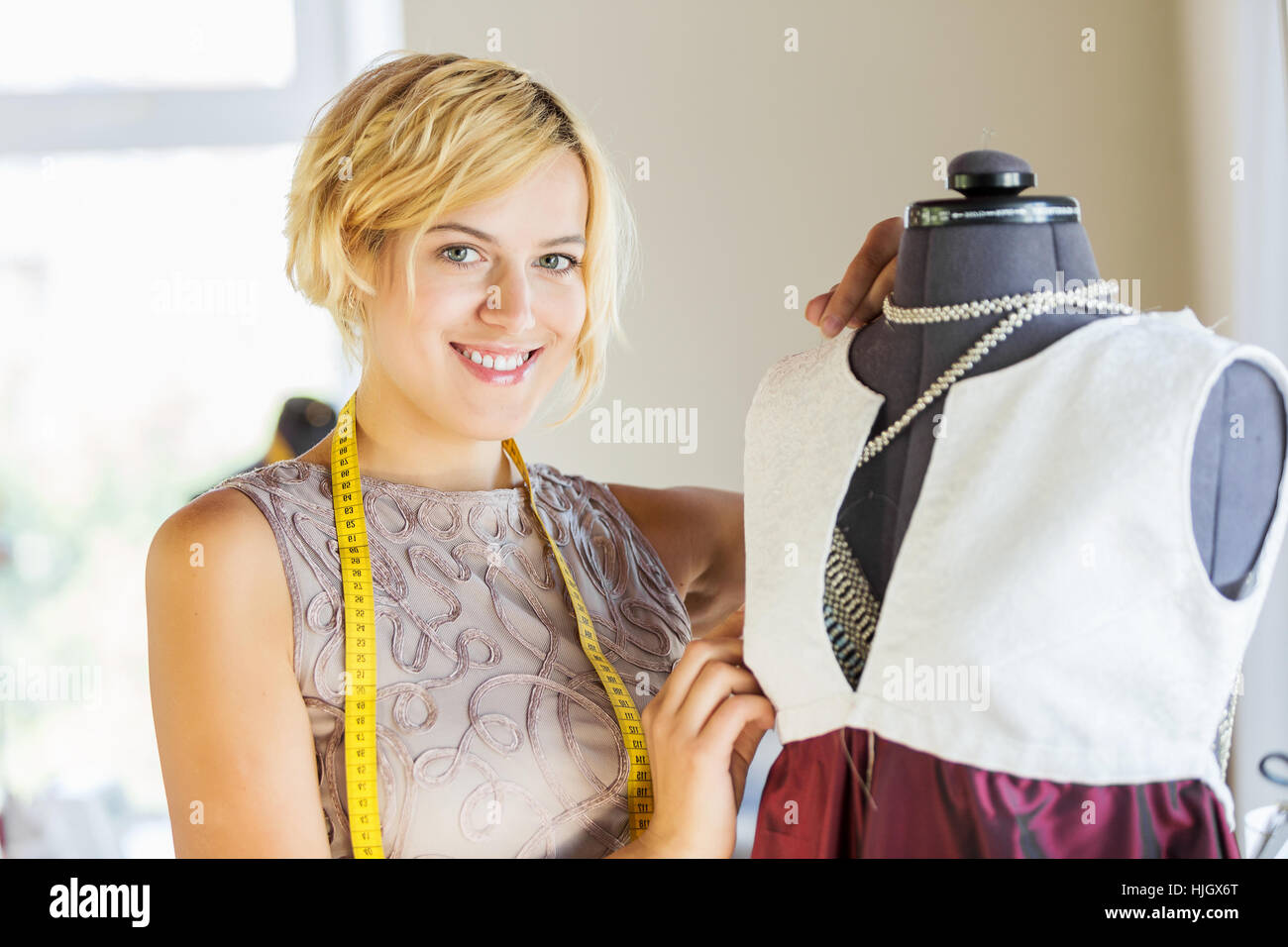 Pretty dressmaker at work pinning dress on dummy Stock Photo - Alamy
