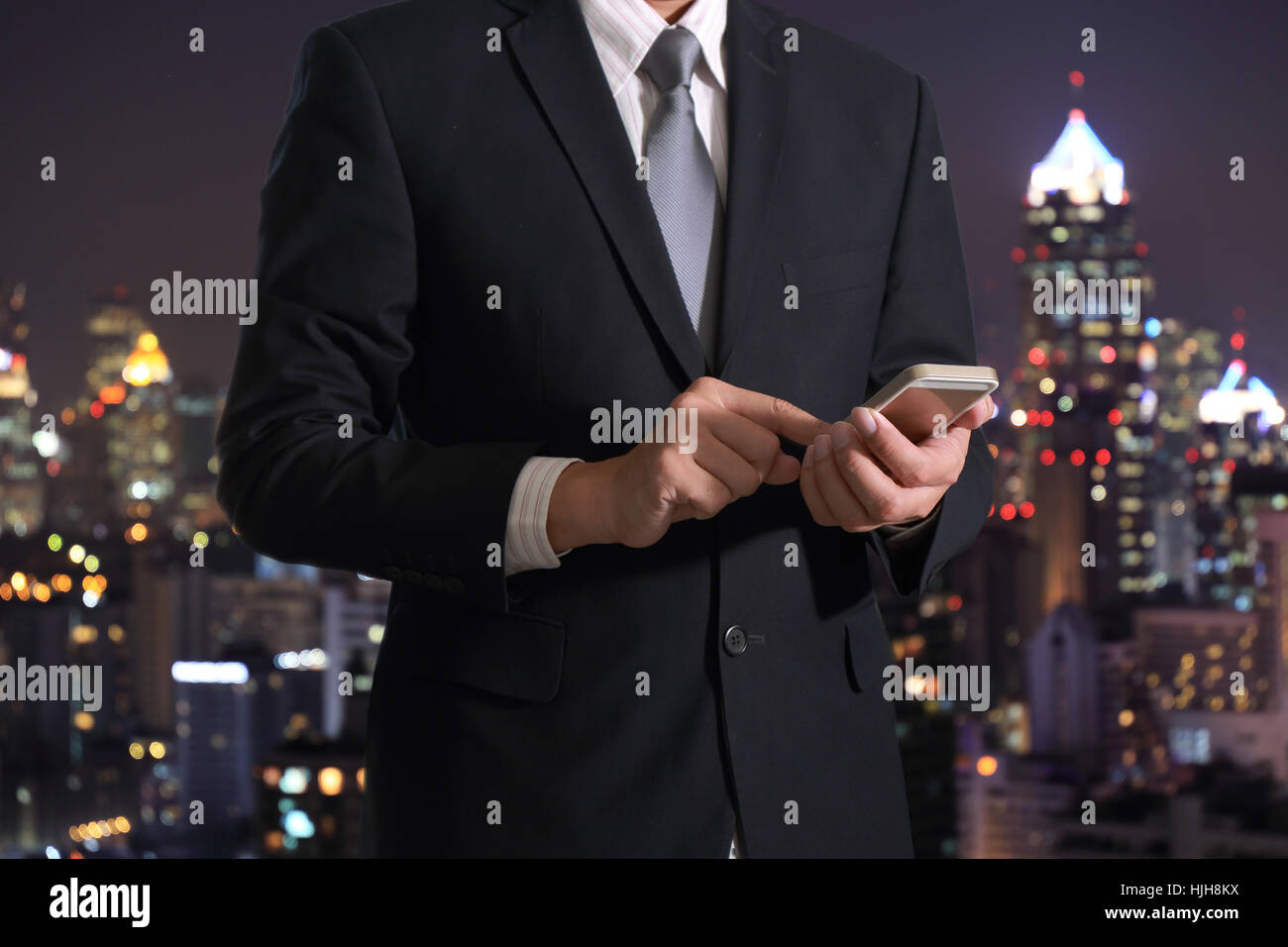 Business man using smart phone on blurred abstract night city background as communication Concept. Stock Photo