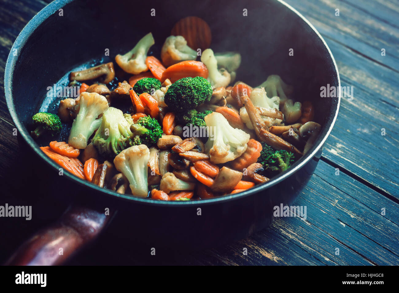 Roasted vegetables in a frying pan on dark wooden boards Stock Photo